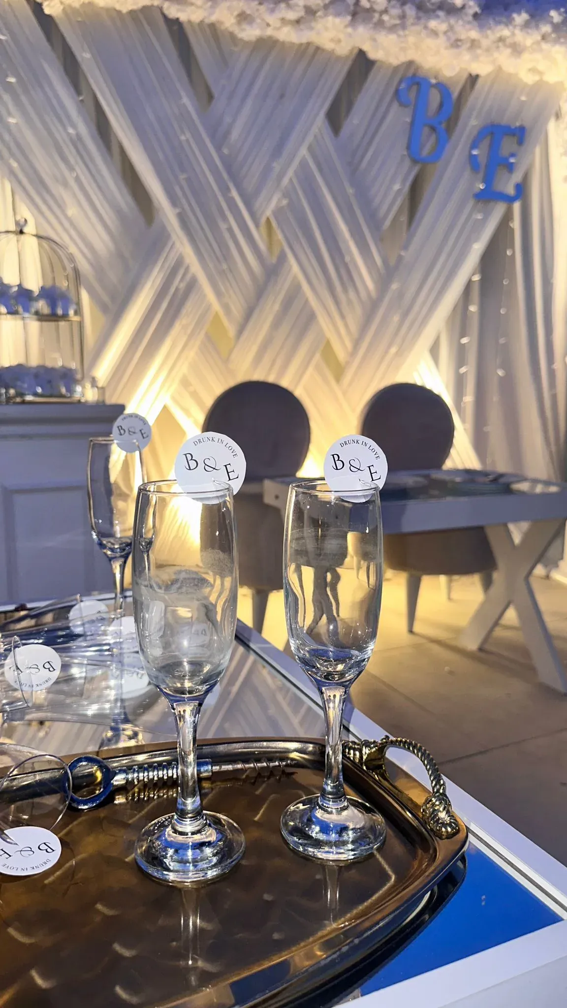 Monogrammed B&E champagne flutes on a silver tray with celebration backdrop